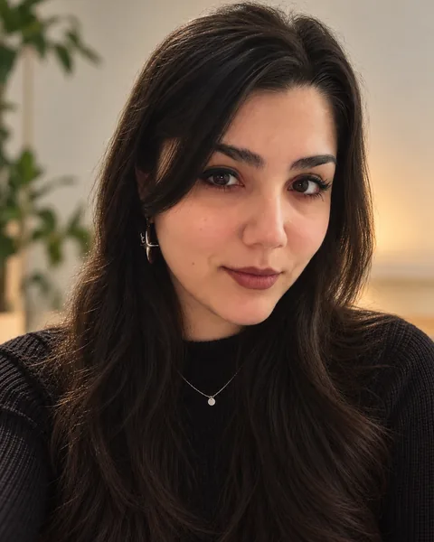 Portrait of Larissa with long dark hair and a black sweater, smiling softly.